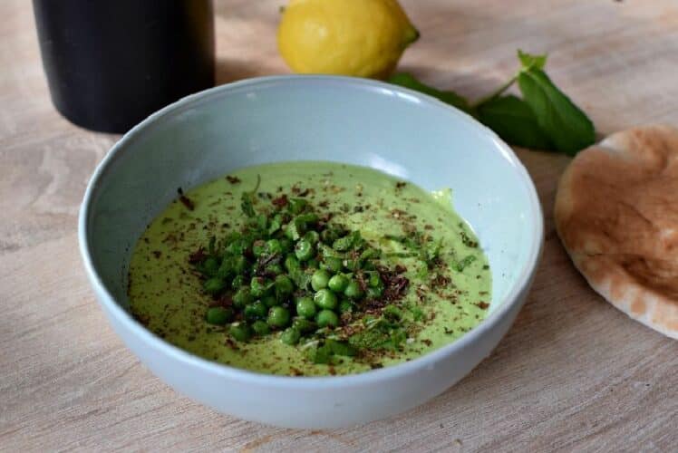 Un bon contenant un houmous vert composé de petits pois, et surmonté de menthe fraiche