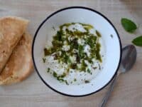 un bol blanc contenant du labné, fromage libanais, à la feta et arrosé d'une huile parfumée à la menthe