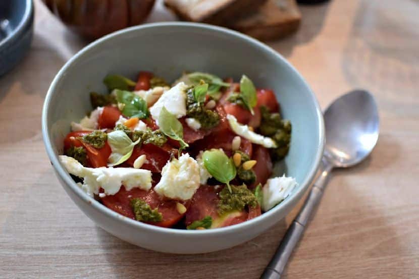 Une assiette creuse contenant une salade tomate mozarella au pesto de basilic