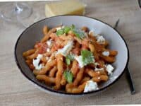 un plat de Pates tomate et ricotta des pâtes imbibées de sauce tomate rouge et parsemée de ricotta fraiche