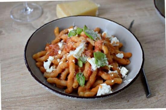un plat de Pates tomate et ricotta des pâtes imbibées de sauce tomate rouge et parsemée de ricotta fraiche