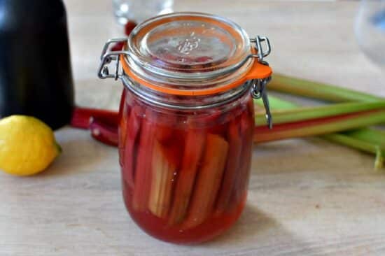 Un bocal contenant des tiges de rhubarbes rouges pochées au sirop