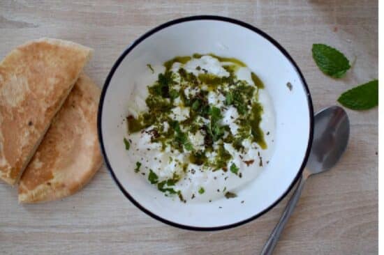 un bol blanc contenant du labné, fromage libanais, à la feta et arrosé d'une huile parfumée à la menthe