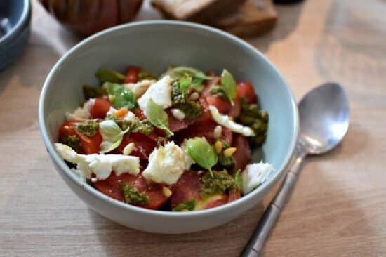 Une assiette creuse contenant une salade tomate mozarella au pesto de basilic